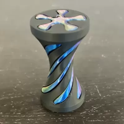 Peça cilíndrica preta com detalhes em azul iridescente e topo com padrão floral