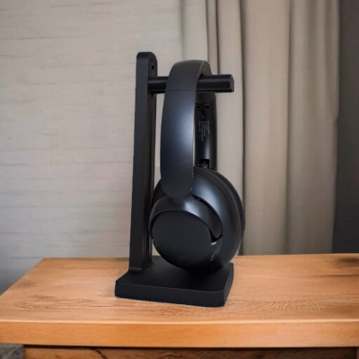 Auscultadores pretos em suporte vertical preto sobre mesa de madeira clara