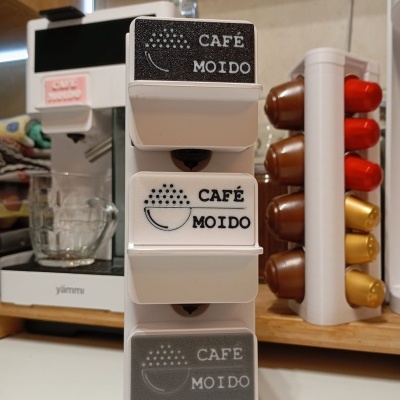 Suporte plástico branco com etiquetas CAFÉ MOIDO e máquina de café branca ao fundo