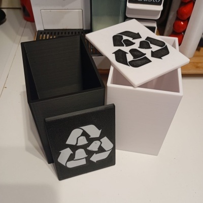 Recipientes quadrados preto e branco com símbolo de reciclagem e cápsulas de café na tampa