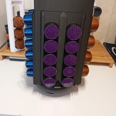 Suporte organizador preto para cápsulas de café coloridas numa bancada branca