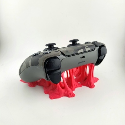 Comando Sony camuflado cinzento e preto sobre suporte vermelho elástico em fundo branco