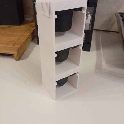 Organizador vertical de cápsulas de café branco com três cápsulas pretas