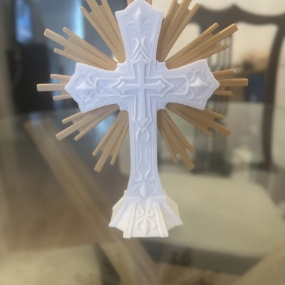 Cruz branca ornamentada com raios dourados em fundo desfocado