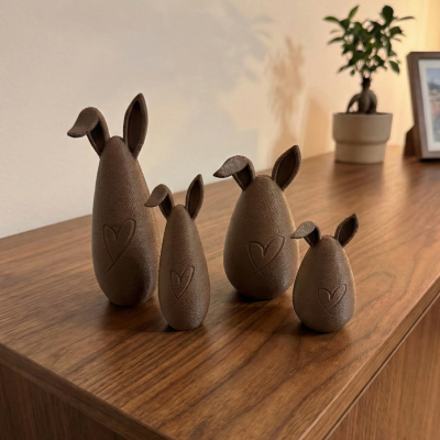 Figuras decorativas castanhas em forma de coelhos com orelhas e coração gravado, sobre móvel de madeira