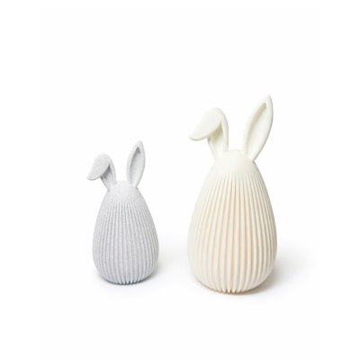 Dois coelhos decorativos de ovo com textura canelada, um cinza claro e outro branco.
