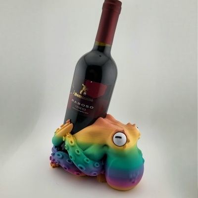 Suporte para garrafa de vinho em forma de polvo colorido segurando uma garrafa de vinho tinto.