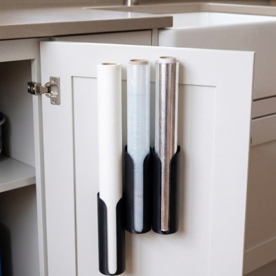 Suporte com três rolos de papel na porta de um armário de cozinha