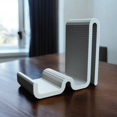 Suporte para telemóvel em plástico branco e cinza com textura ondulada sobre mesa de madeira