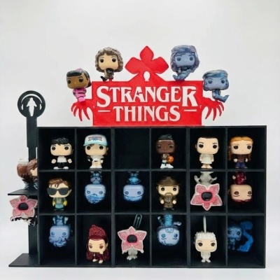 Conjunto de mini figuras da série Stranger Things em prateleira preta com divisórias e sinal vermelho com o texto Stranger Things