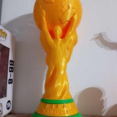 Troféu dourado FIFA World Cup com detalhes verdes numa superfície de madeira