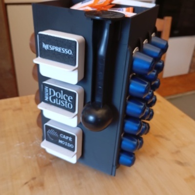 Suporte preto para cápsulas de café com cápsulas azuis e etiquetas NESPRESSO, Dolce Gusto e CAFÉ MOÍDO