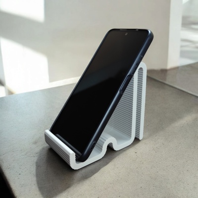 Suporte branco para telemóvel com telemóvel preto em cima de superfície de pedra.