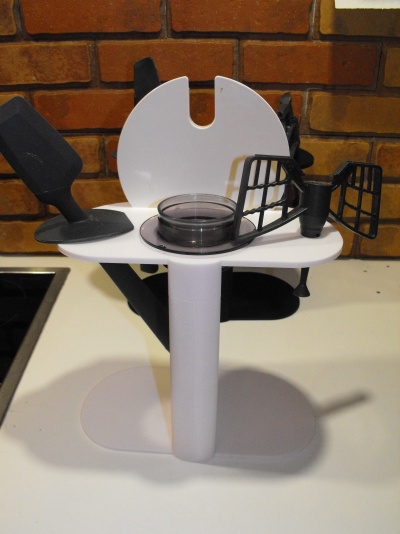 Acessórios de cozinha em plástico e borracha com espátula e suporte branco sobre superfície branca