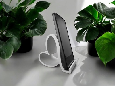 Suporte de smartphone branco em forma de coração com smartphone preto entre plantas verdes em vasos pretos.