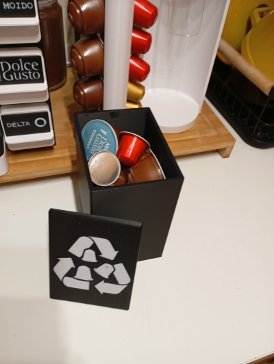 Recipiente preto com cápsulas de café coloridas e símbolo de reciclagem