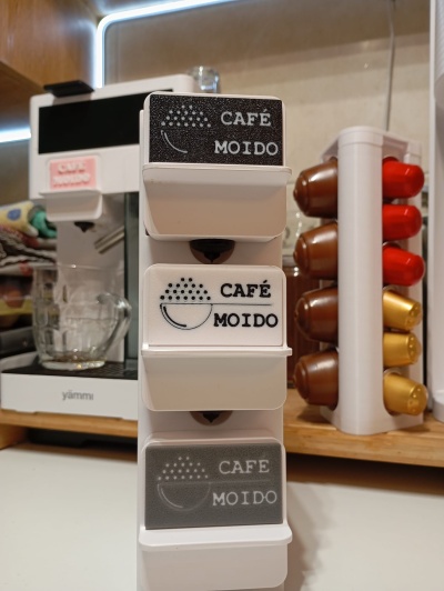Suporte plástico branco com etiquetas CAFÉ MOIDO e máquina de café branca ao fundo