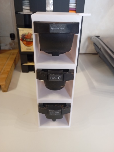 Organizador branco com cápsulas de café preto marcadas com NESPRESSO, DELTA e CAFE MOIDO