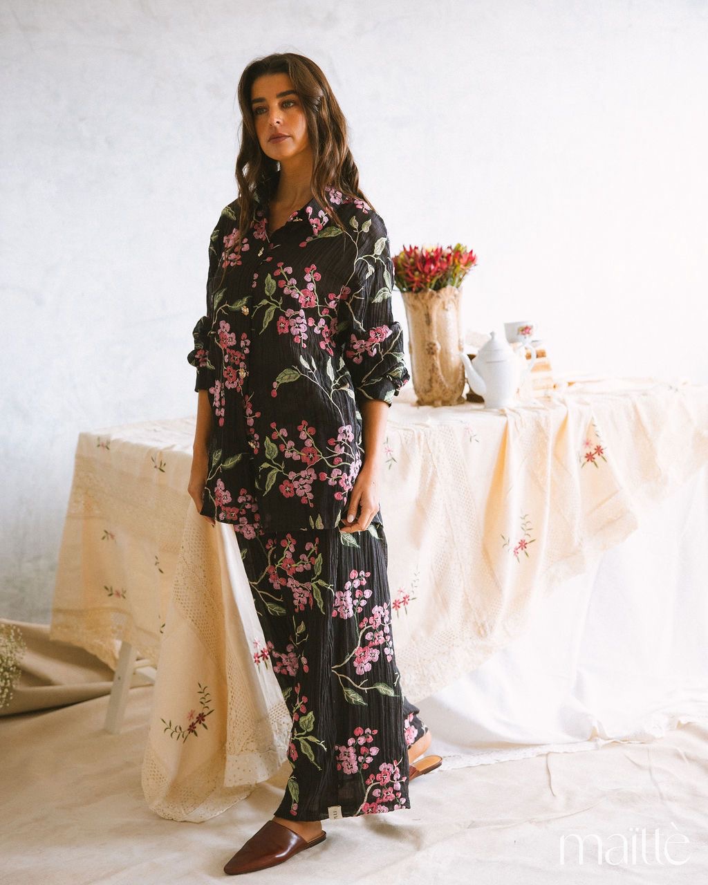 CONJUNTO ROSANETE Conjunto de camisa e calças florais negras com padrão rosa e verde em ambiente interior