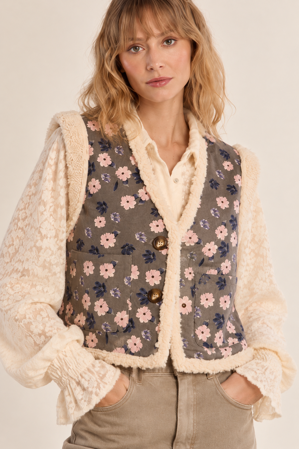 COLETE CHEILA Colete floral com guarnição felpuda em mulher vestindo camisa de renda e calças bege