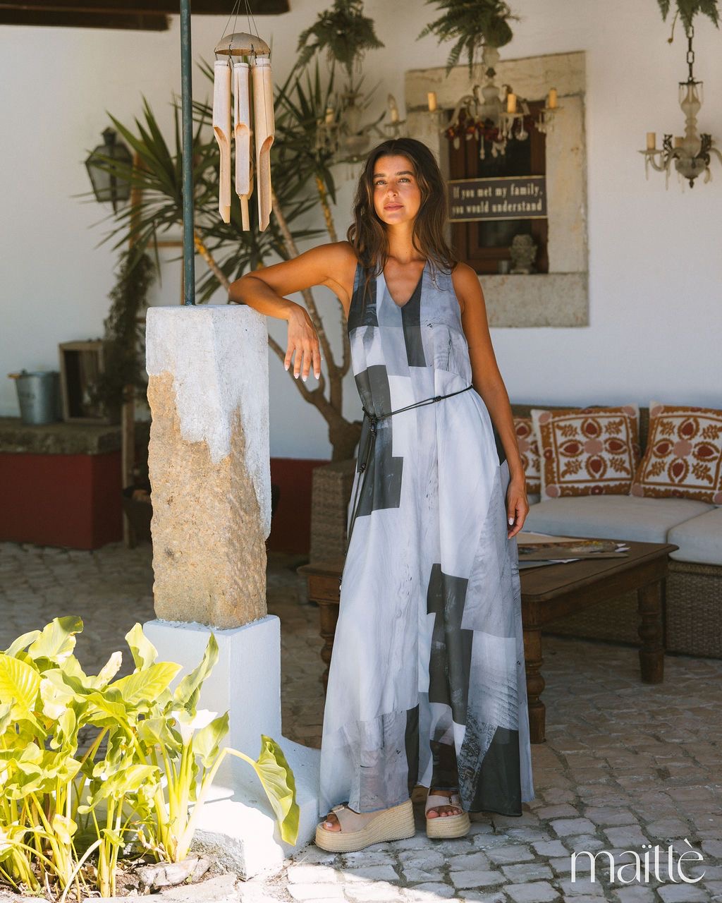 VESTIDO ADOSINDA Mulher com vestido maxi cinza e preto com cinto, sandálias de plataforma, ambiente rústico exterior