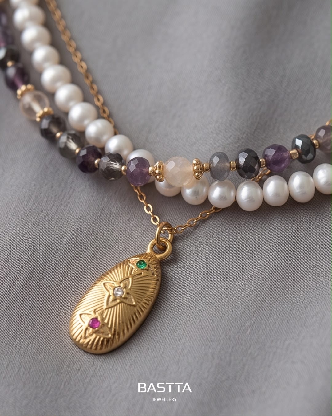 FIO BENICE Colar duplo com pérolas e contas facetadas com pendente dourado sobre tecido cinza