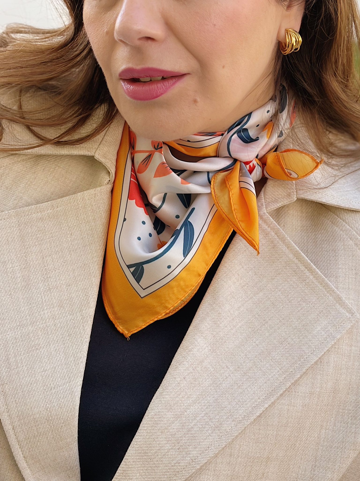 LENÇO SÃO MARTINHO Lenço colorido com padrão floral ao pescoço com casaco bege.