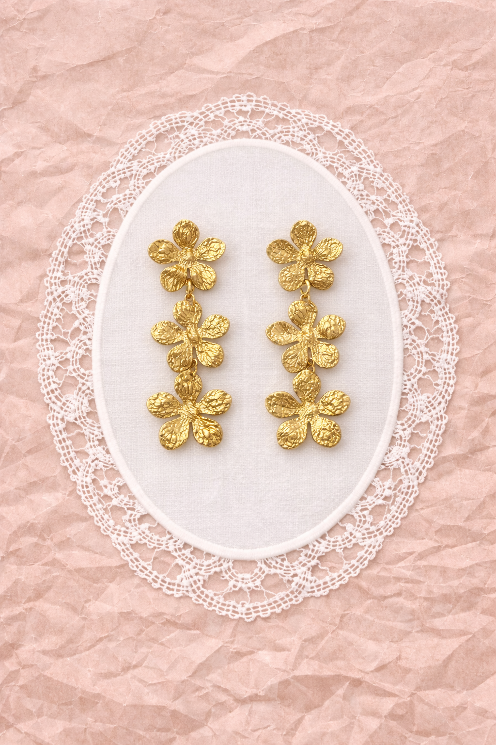 BRINCOS CALÊNDULA Brincos dourados em forma de flores com fundo rendado branco e papel rosa