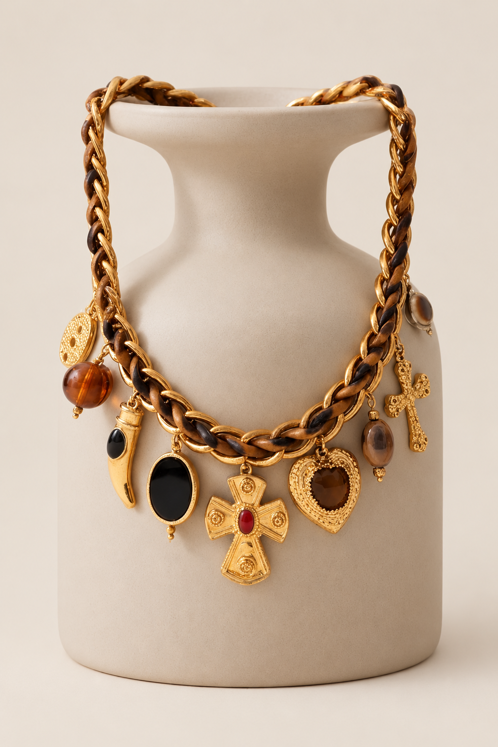 COLAR BENITA Colar dourado com pendentes variados exposto numa jarra cinza