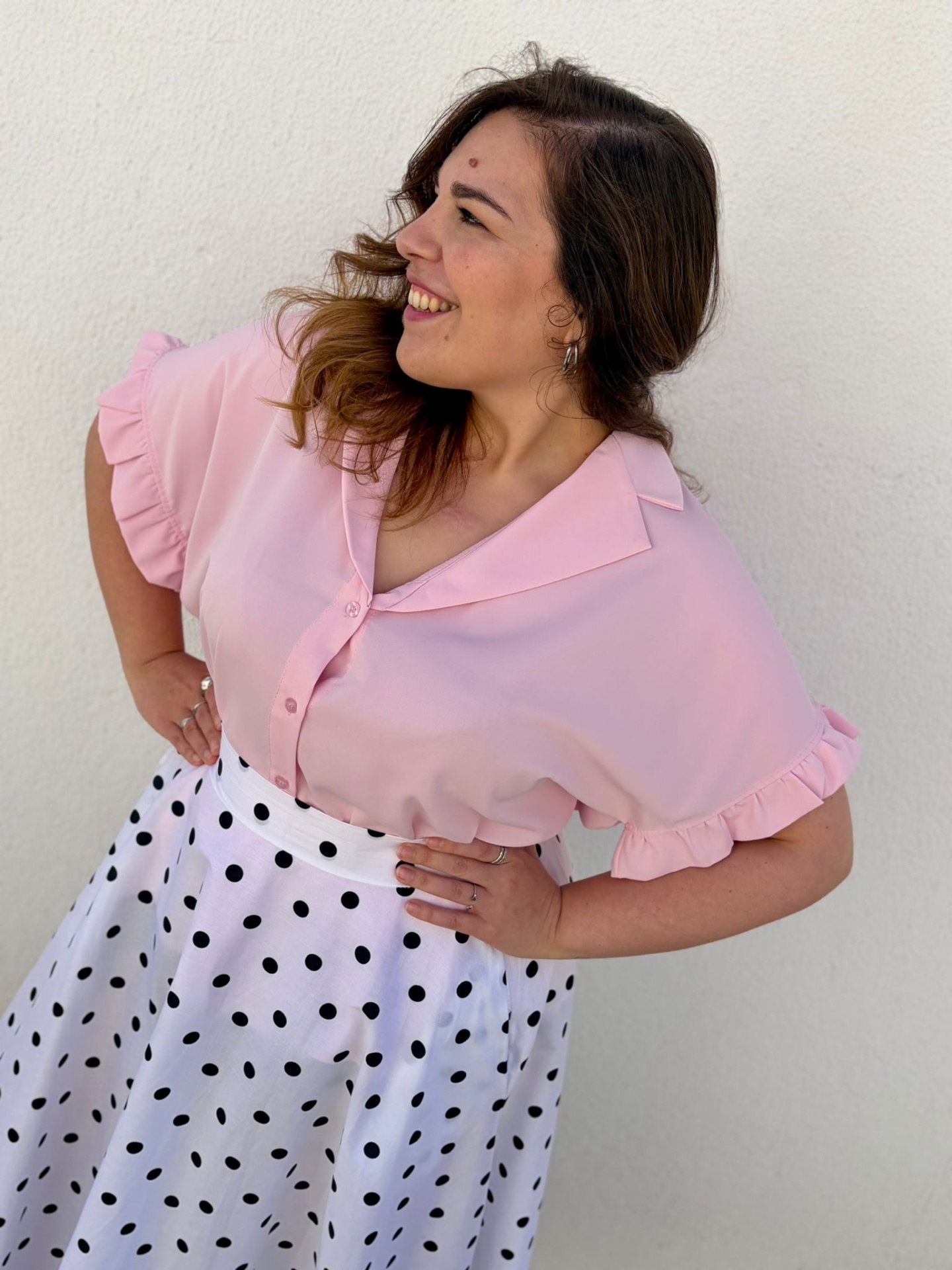 CAMISA YANA Mulher com blusa rosa de manga curta com folhos e saia branca com bolinhas pretas