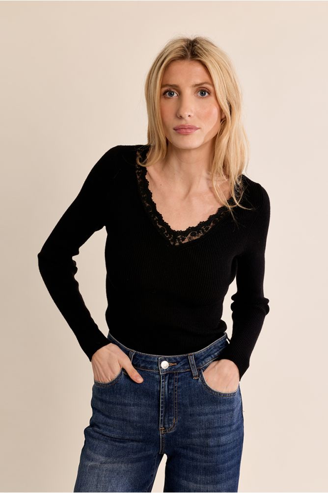 CAMISOLA ÂNIA PRETO Mulher com camisola preta de malha com renda e jeans azuis de cintura alta.