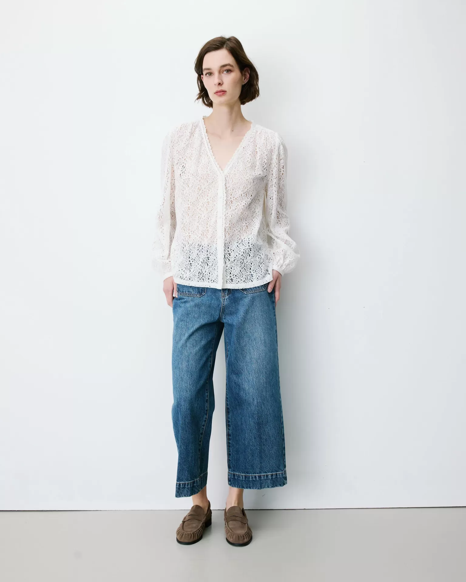BLUSA AURORA BRANCO Blusa branca de renda com mangas compridas, jeans azuis largos e sapatos castanhos