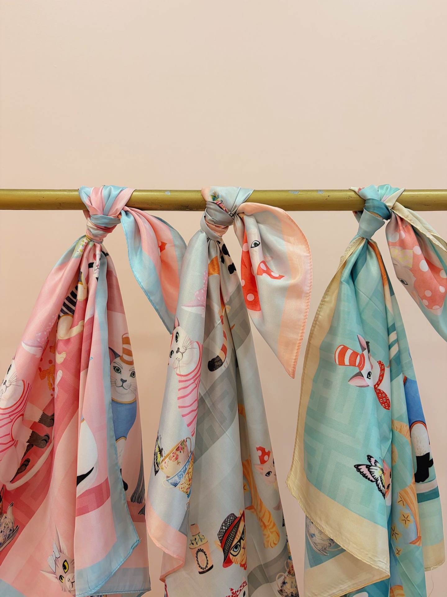 LENÇO CAT LADY Lenços decorativos com padrões de gatos coloridos pendurados num suporte dourado