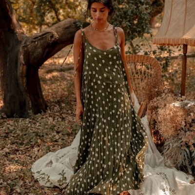 Vestido comprido verde com bolinhas brancas, mulher ao ar livre com cadeira de vime e candeeiro