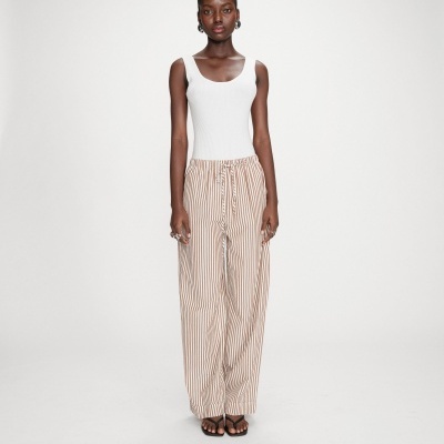 Mulher com top branco e calças largas riscas castanhas