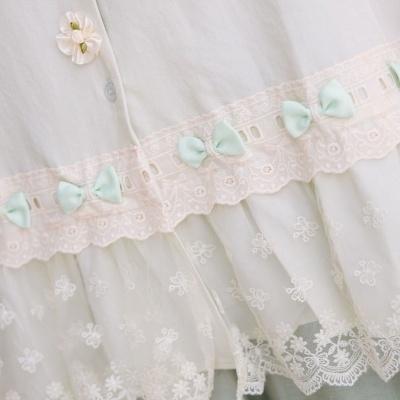 Blusa branca com renda floral e detalhes em laços verdes e botão decorativo