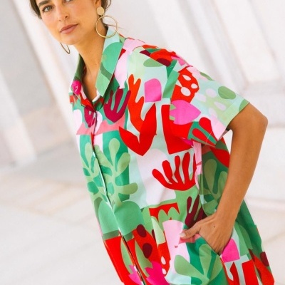 Vestido colorido com padrão abstrato e brincos grandes dourados em fundo claro
