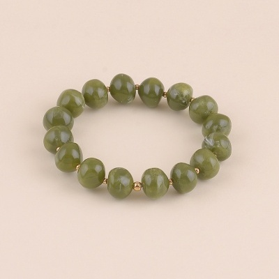Pulseira de contas verdes e douradas em fundo bege claro