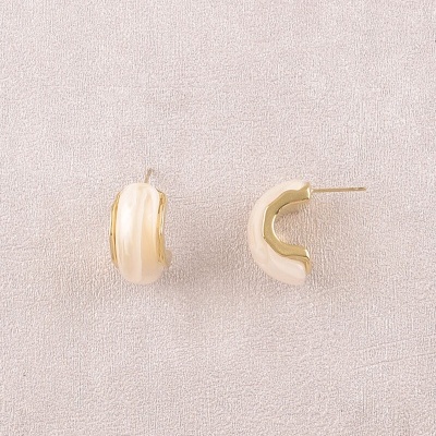Brincos de argola creme com detalhe dourado sobre fundo neutro