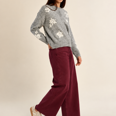 Mulher com camisola cinzenta com flores, calças largas vinhas e ténis brancos