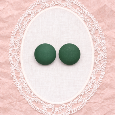 Dois botões verdes sobre tecido branco bordado com renda em papel rosa amassado