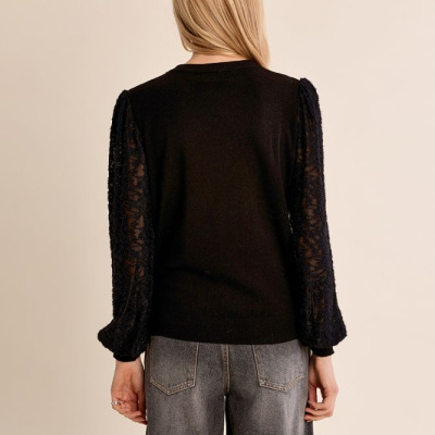 Camisola preta com mangas em renda e jeans cinza vista de costas
