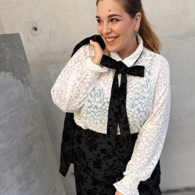 Mulher a usar blusa branca de renda com laço preto