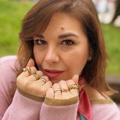 Mulher com camisola rosa e anéis dourados e prateados