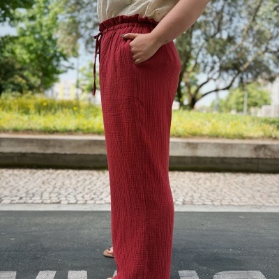 Calças largas vermelhas com cordão na cintura e blusa branca com padrão floral
