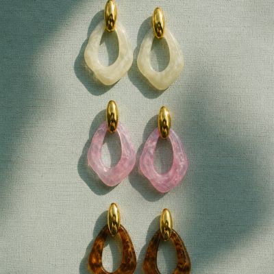 Três pares de brincos com pendentes geométricos em creme, rosa e castanho com base oval dourada