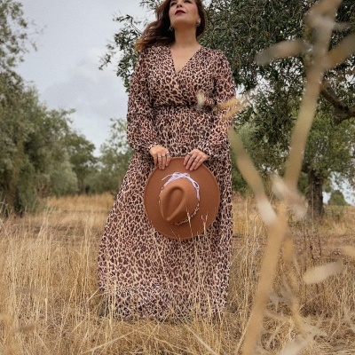 Vestido longo animal print castanho bege preto e chapéu castanho com detalhes brancos, ao ar livre em campo seco