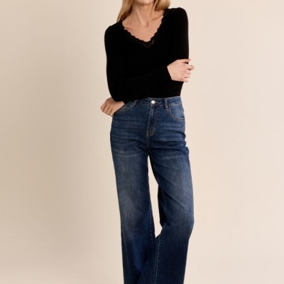 Mulher com camisola preta de manga longa e jeans azuis largos