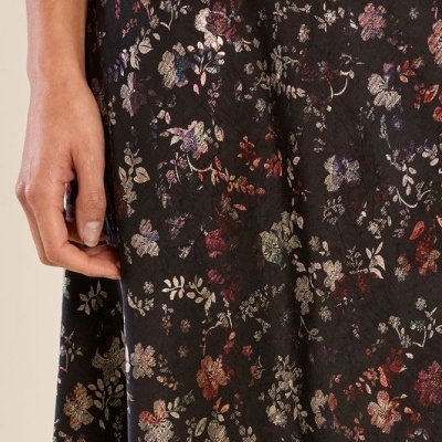 Tecido preto com padrão floral colorido e mão feminina ao lado
