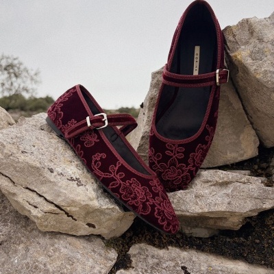 Sapatos femininos de veludo bordô com bordado floral e fivela prateada em pedras cinzentas.